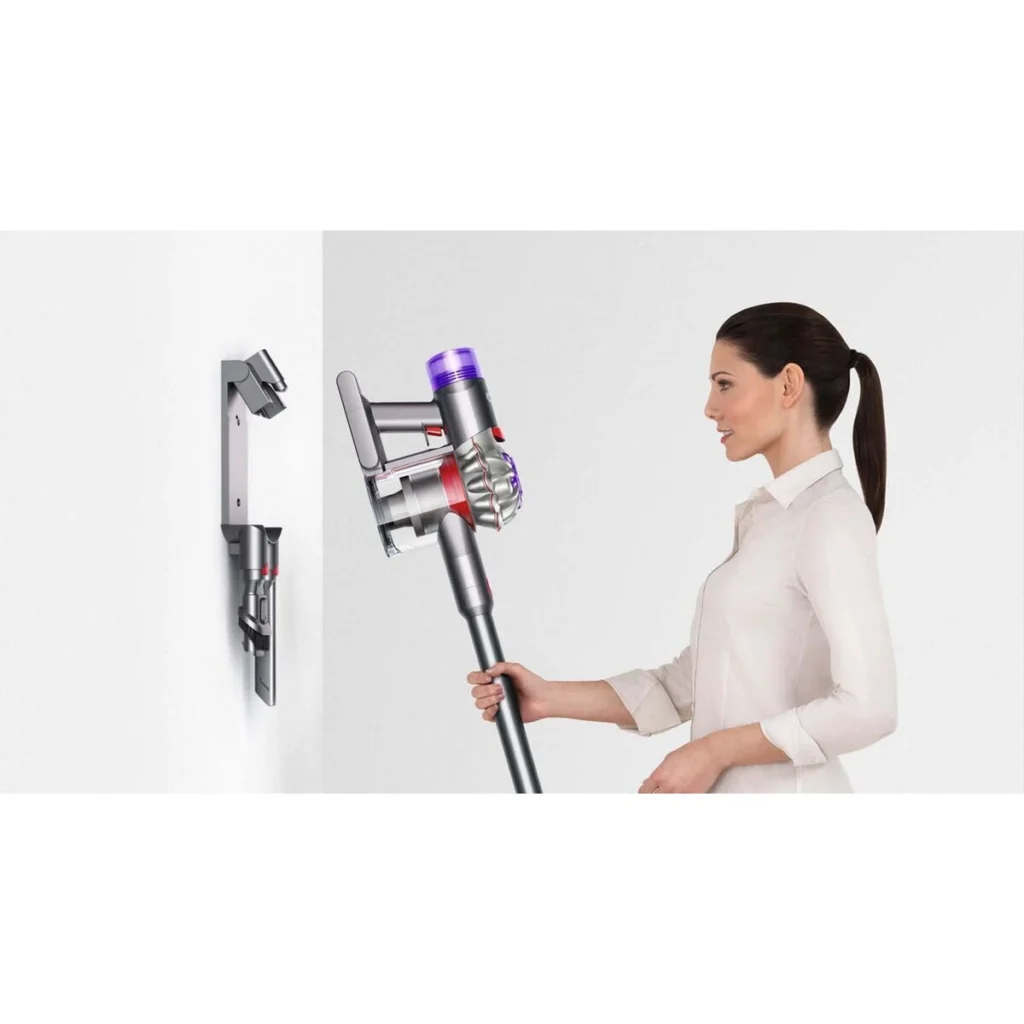 Une femme range le Dyson V8 Advanced sur sa station murale