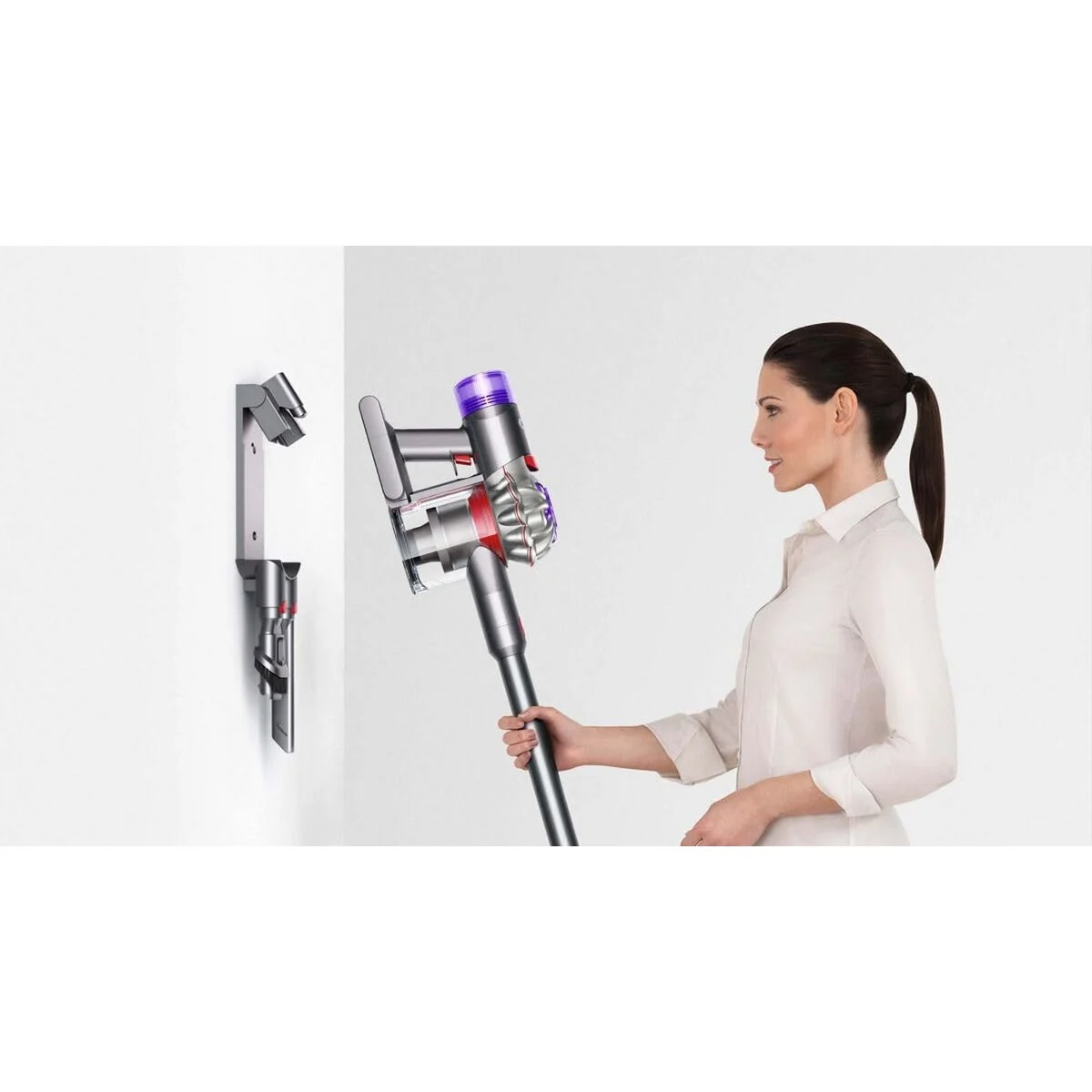 Une femme range le Dyson V8 Advanced sur sa station murale
